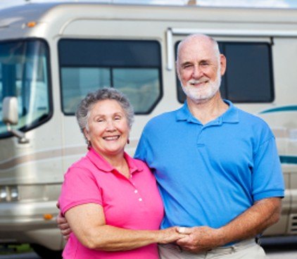 A smiling couple standing in front of their motorhome